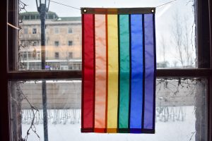 A LGBT flag hangs in front of a window in the LGBTCC