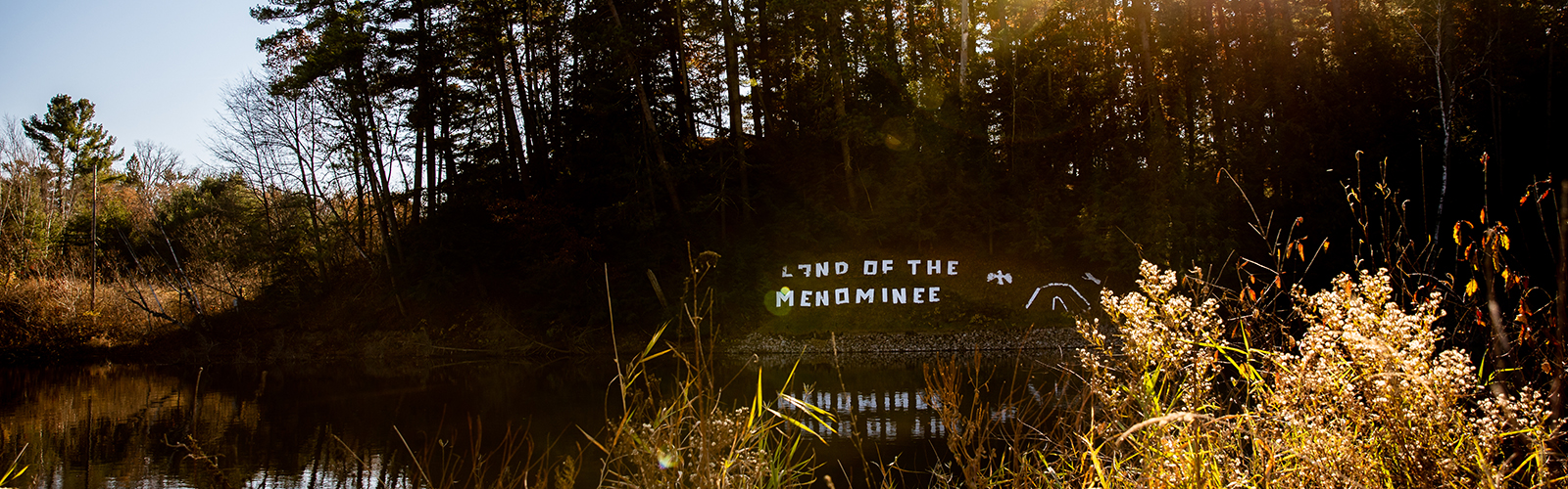 In the Menominee Veteran's Park in Keshena, “Land of the Menominee” appears on the banks of the Wolf River.